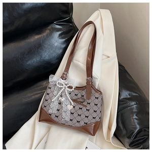 Detail of vintage plaid tote bag featuring lace bow and pearl heart pendant charm
