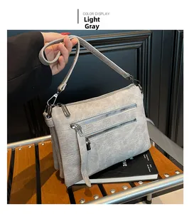 Close-up of light grey multi-zipper crossbody bag with textured faux leather finish