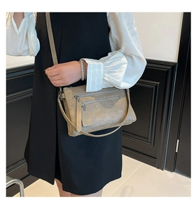 Détail du sac bandoulière taupe vintage avec deux fermetures éclair et longues tirettes en cuir