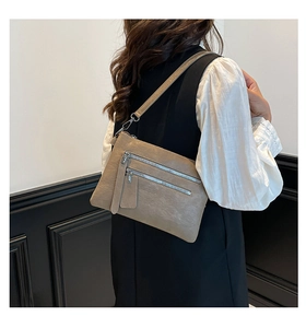 Détail du sac bandoulière en cuir kaki avec fermetures éclair argentées et fine sangle