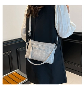 Détail d'un sac bandoulière gris clair à fermetures éclair avec garniture argentée
