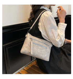 Détail du sac bandoulière gris vintage avec doubles zips frontaux et cuir synthétique texturé