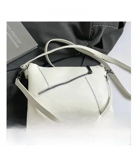 Detailed macro view of white lychee pattern leather and diagonal zipper on crossbody bag