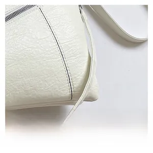Close-up of white soft leather handbag showing pebbled texture and silver metal zipper