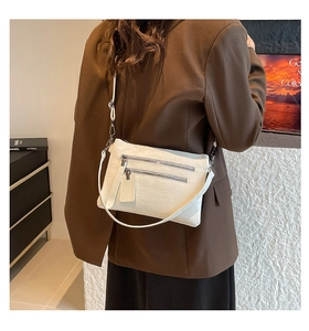 Close-up of a white lychee grain leather crossbody bag with dual front zipper pockets