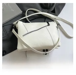 Detail of white soft leather crossbody bag with black contrast stitching and zipper