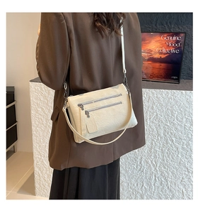 Close-up detail of cream white crossbody bag with multi-zipper pockets and litchi texture