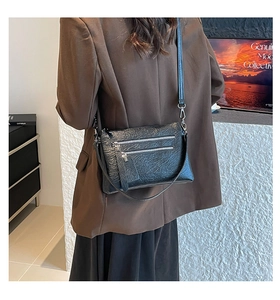 Gros plan du sac bandoulière en cuir froissé noir avec trois fermetures argent