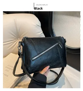 Detail view of black PU leather crossbody bag with silver hardware and front zipper texture