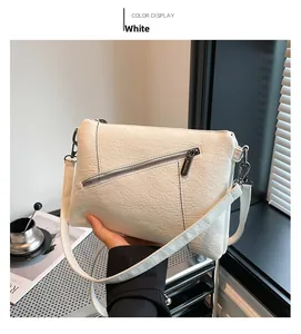 Detailed view of white textured leather crossbody bag with diagonal silver zipper accents