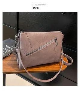 Detail view of pink crossbody bag with triple-layer accordion structure and zippers