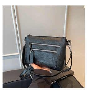 Close-up of vintage textured black leather bag with multiple zippers and silver hardware