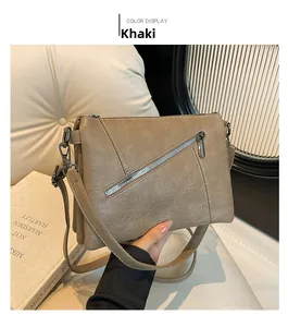 Close-up of khaki shoulder bag with textured leather and diagonal silver zipper detail