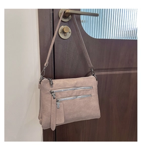 Detail of dusty pink PU leather shoulder bag with functional zippers and metallic hardware