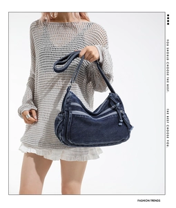 Detailed view of dark blue denim crossbody bag featuring functional multi-zipper pockets