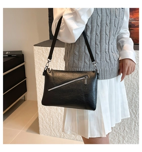 Detail of black textured leather bag with silver zipper and detachable shoulder strap