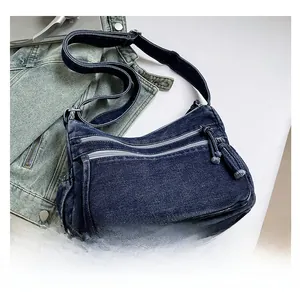 Detail of vintage blue denim crossbody bag with multiple zipper pockets and wide strap