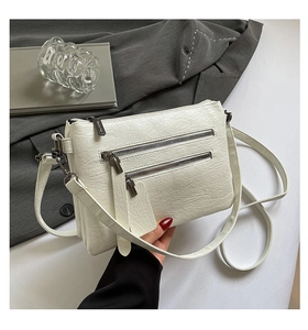 Détail du sac à bandoulière blanc en similicuir plissé avec doubles poches zippées