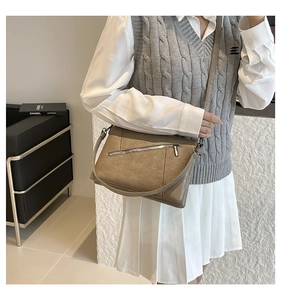 Detail view of brown soft leather crossbody bag with minimalist diagonal zipper design
