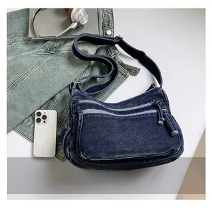 Detail view of deep blue denim crossbody bag with multiple pockets and adjustable strap