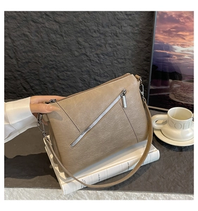 Detail of soft leather shoulder bag featuring diagonal metal zipper and fine grain texture