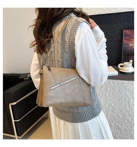 Detail of khaki leather crossbody bag showing multi-layer structure and zipper design