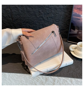 Detail of dusty pink crossbody bag showing triple zipper compartments and smooth PU leather