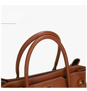 Dettaglio borsa in pelle a grana con cuciture bianche a contrasto e finiture dorate