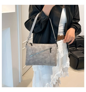 Detail view of the gray soft leather handbag with textured surface and diagonal zipper