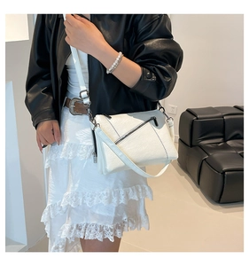 White faux leather crossbody bag with zipper detail shown on a model in a modern interior