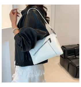 Detail of white leather shoulder bag with diagonal zipper and sleek charcoal hardware