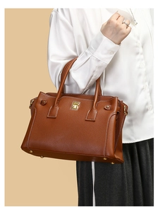 Dettaglio della borsa in pelle martellata marrone con chiusura a scatto dorata e manici