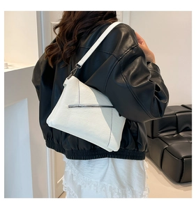 White textured PU leather crossbody bag worn by a model in a black leather jacket