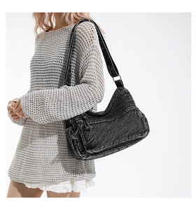 Close-up of vintage black denim shoulder bag with multiple functional zip pockets