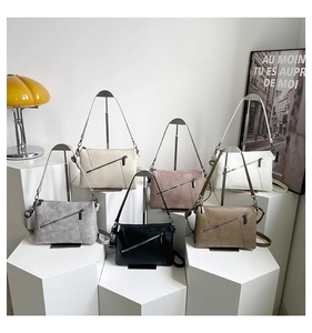 Multiple textured crossbody bags in various colors displayed on geometric blocks