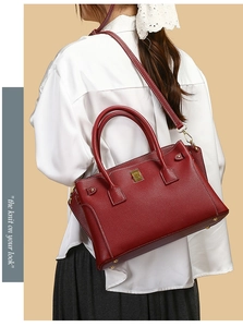 Dettaglio borsa in pelle rosso scuro con cuciture bianche e finiture in metallo oro