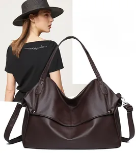 Detail of dark brown tote bag featuring textured pebble leather and adjustable shoulder strap