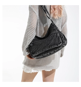 Detail of vintage washed denim tote bag with functional exterior zippers on dark fabric