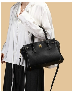 Vista laterale della modella con borsa tote in pelle nera e chiusura girevole dorata