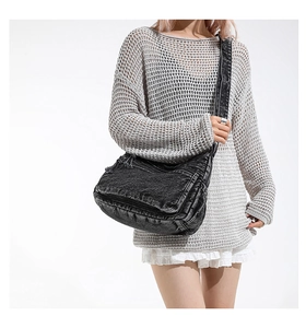 Detail view of washed black denim crossbody bag with adjustable silver buckle and wide strap