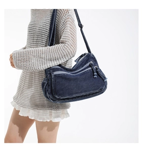 Deep blue denim crossbody bag with multiple zipper pockets and adjustable strap on model