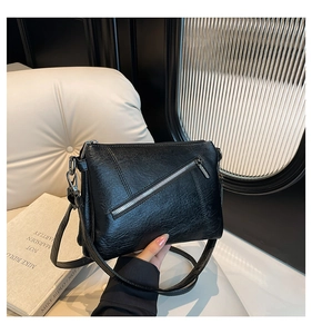 Detail of black lychee grain leather crossbody bag with silver zipper and metal hardware