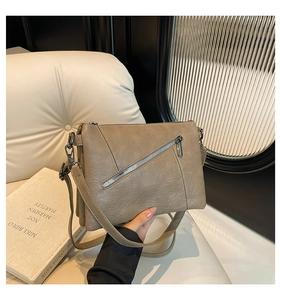 Close-up of khaki lychee grain leather crossbody bag with silver metal zipper detail