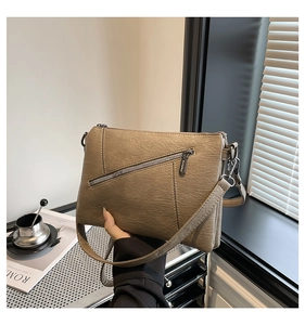 Detail of khaki PU leather bag featuring diagonal zipper and layered accordion structure