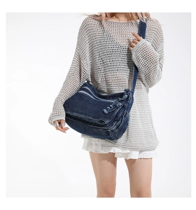 Detail of dark blue denim crossbody bag featuring multiple zippers and adjustable strap