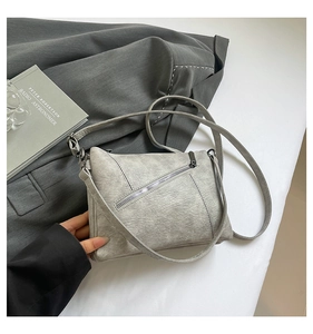 Detailed view of grey vintage textured leather crossbody bag with diagonal zip pockets
