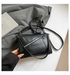 Close-up of black pebbled leather texture and silver zipper detail on messenger bag