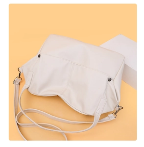 Detail of off-white lychee texture leather shoulder bag with silver rivets and metal buckle