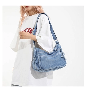 Detail of blue denim crossbody bag featuring multiple zipper pockets and Y2K vintage style