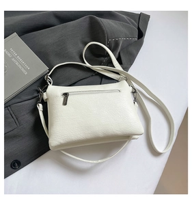 Detail of white lychee-textured PU crossbody bag with back zipper pocket on grey blazer